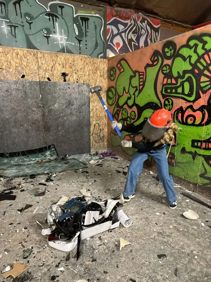Person in protective gear smashing items in rage room - stress relief experience